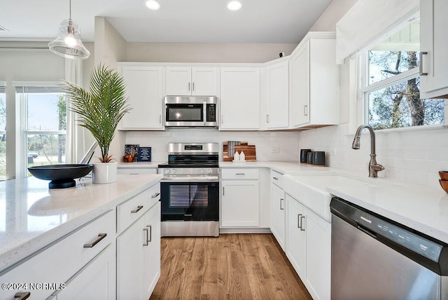 kitchen featuring white cabinetry, a healthy amount of sunlight, light hardwood / wood-style flooring, and stainless steel appliances