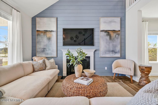 living room featuring lofted ceiling, plenty of natural light, hardwood / wood-style floors, and wooden walls