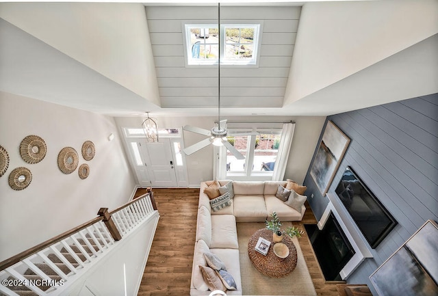 living room with ceiling fan with notable chandelier, dark hardwood / wood-style flooring, and high vaulted ceiling