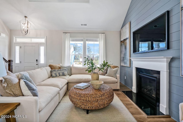 living room featuring lofted ceiling, hardwood / wood-style floors, and a chandelier