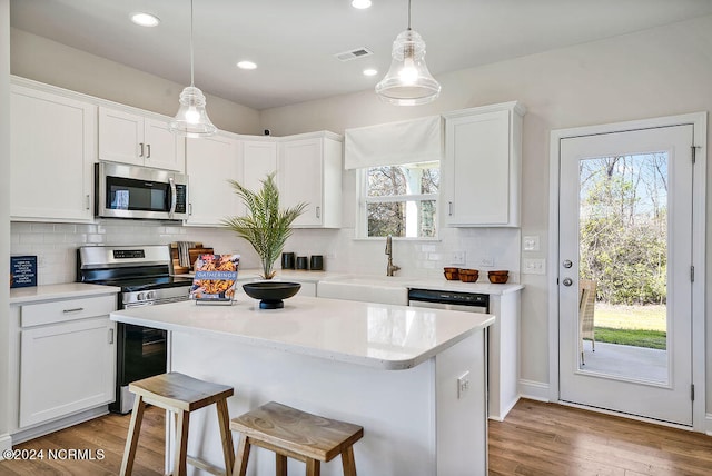 kitchen with a wealth of natural light, hanging light fixtures, a center island, and appliances with stainless steel finishes