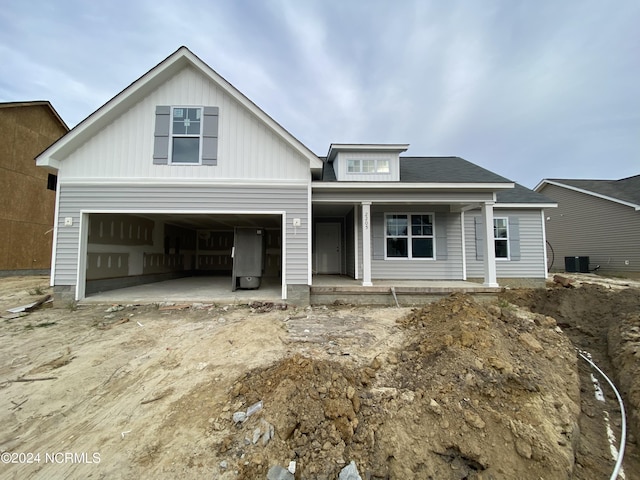 view of front facade featuring a porch, central AC, and a garage