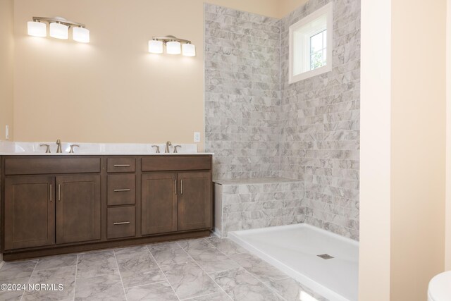 bathroom with tiled shower and vanity