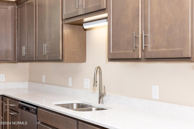 kitchen featuring light stone counters, stainless steel dishwasher, sink, and dark brown cabinetry