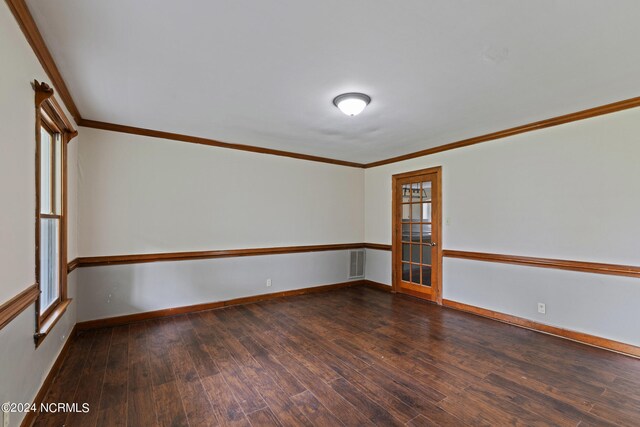 empty room with ornamental molding and dark hardwood / wood-style floors