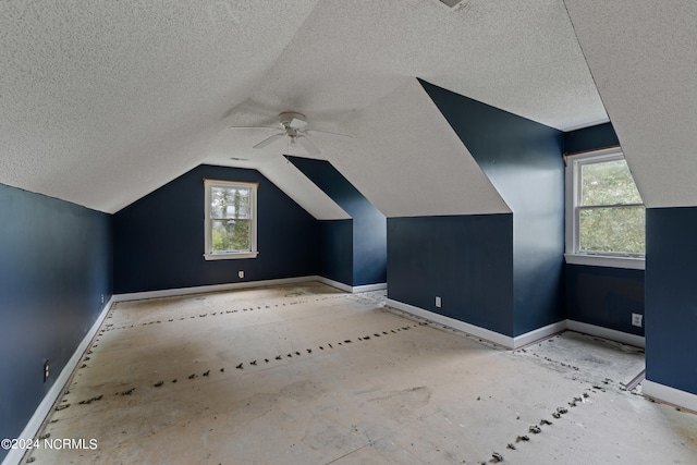 bonus room with lofted ceiling, ceiling fan, plenty of natural light, and a textured ceiling