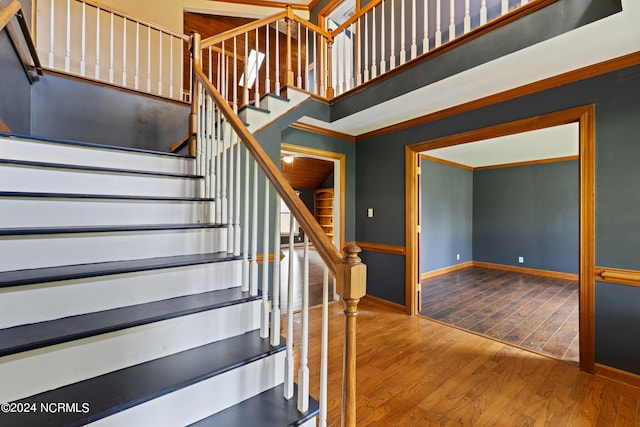 stairs featuring crown molding and hardwood / wood-style floors