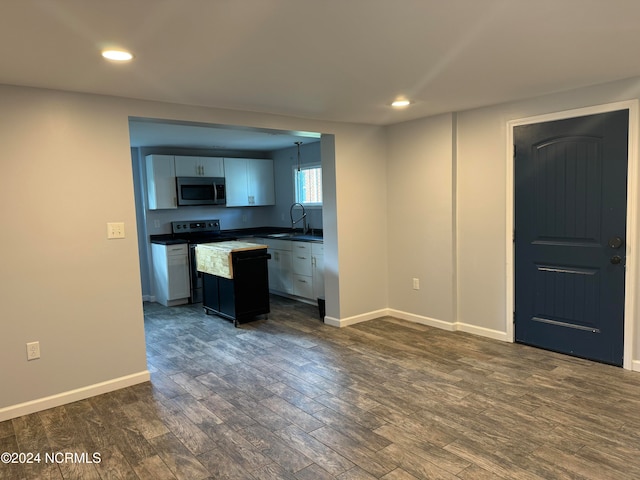 kitchen featuring sink, a kitchen island, hanging light fixtures, white cabinets, and dark wood-type flooring