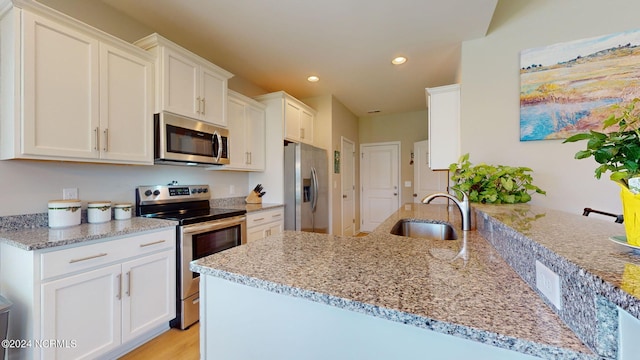 kitchen with white cabinetry, stainless steel appliances, kitchen peninsula, and sink