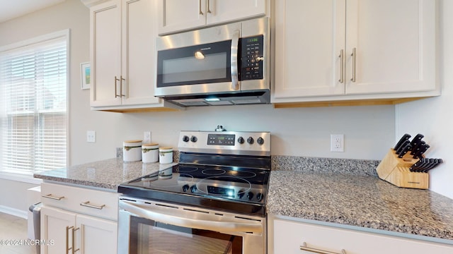 kitchen featuring light stone counters, stainless steel appliances, and white cabinets