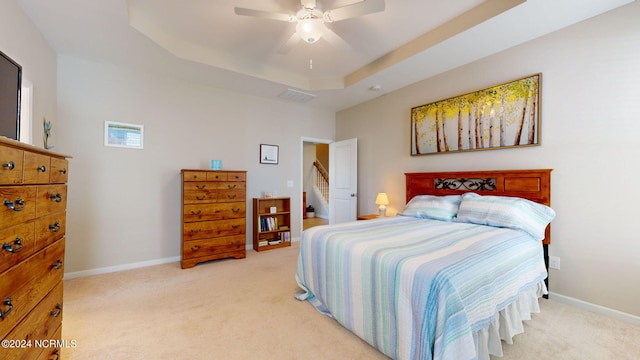 carpeted bedroom with a raised ceiling and ceiling fan