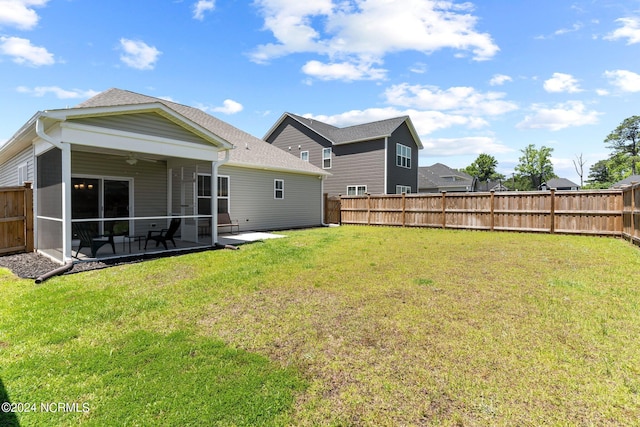 rear view of house featuring a patio, a sunroom, and a lawn