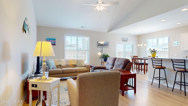 living room featuring vaulted ceiling, a healthy amount of sunlight, ceiling fan with notable chandelier, and light hardwood / wood-style flooring