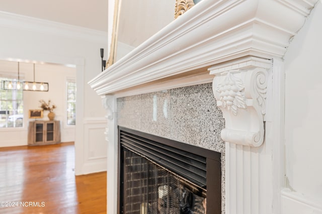 details featuring ornamental molding, a high end fireplace, and hardwood / wood-style flooring