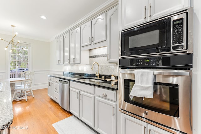 kitchen with dark stone counters, stainless steel appliances, light hardwood / wood-style floors, and sink