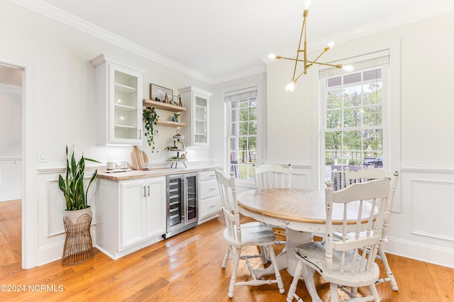 dining room featuring beverage cooler, crown molding, light hardwood / wood-style floors, and a wealth of natural light