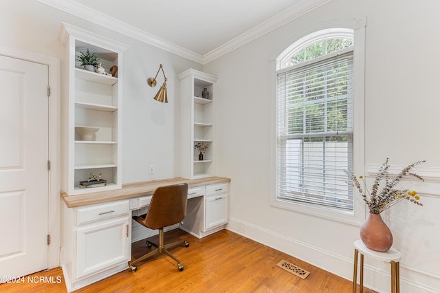 office space with light hardwood / wood-style flooring, built in desk, and ornamental molding