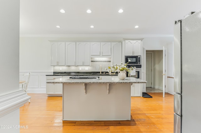 kitchen with light stone countertops, stainless steel appliances, light hardwood / wood-style floors, and a center island