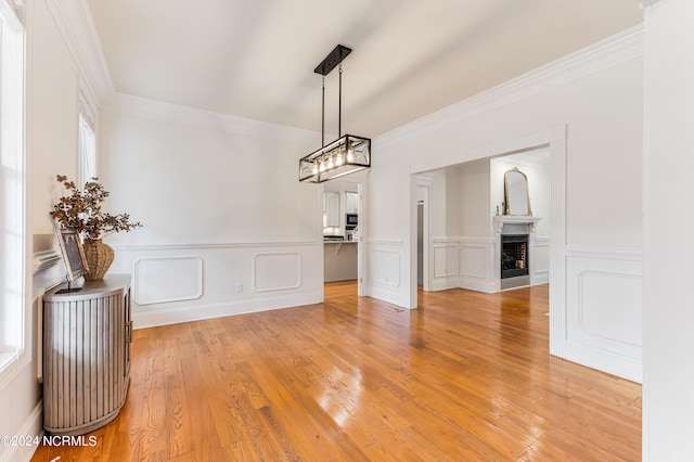 unfurnished dining area with light wood-type flooring, crown molding, and a wealth of natural light