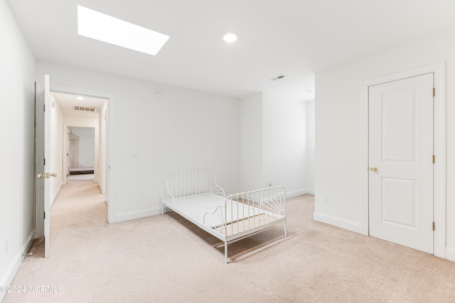 unfurnished bedroom featuring a skylight and light colored carpet