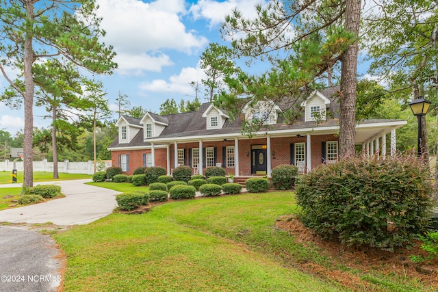 cape cod home with a front yard and a porch