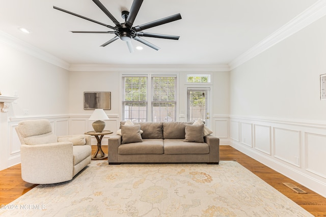 living room with crown molding, light hardwood / wood-style floors, and ceiling fan