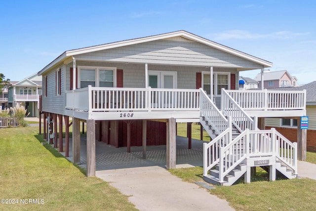 coastal inspired home featuring a front lawn, a carport, and covered porch