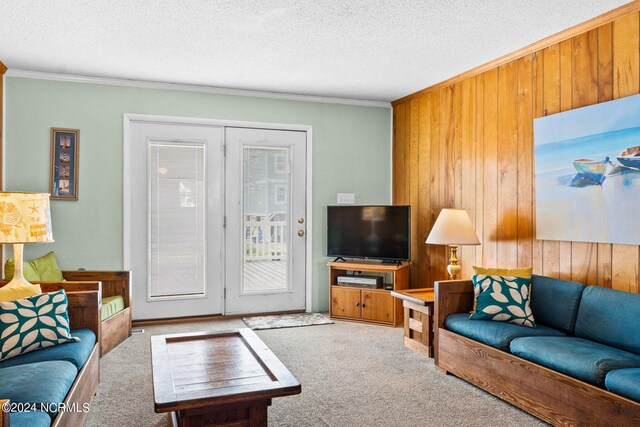 carpeted living room with ornamental molding, wooden walls, and a textured ceiling