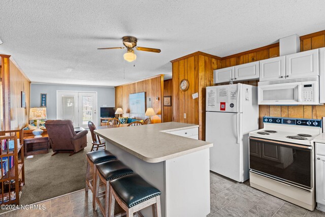 kitchen featuring white cabinets, white appliances, a breakfast bar area, a center island, and ceiling fan