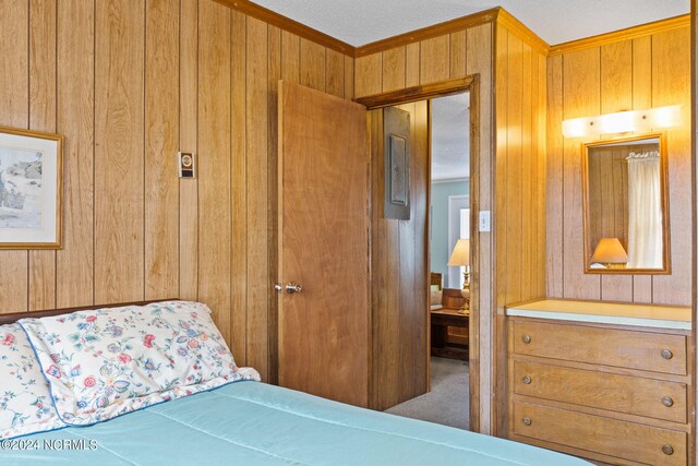 bedroom with carpet, wood walls, a textured ceiling, and ornamental molding