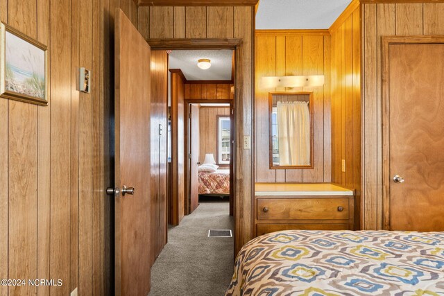 bedroom featuring wooden walls, a textured ceiling, and carpet flooring