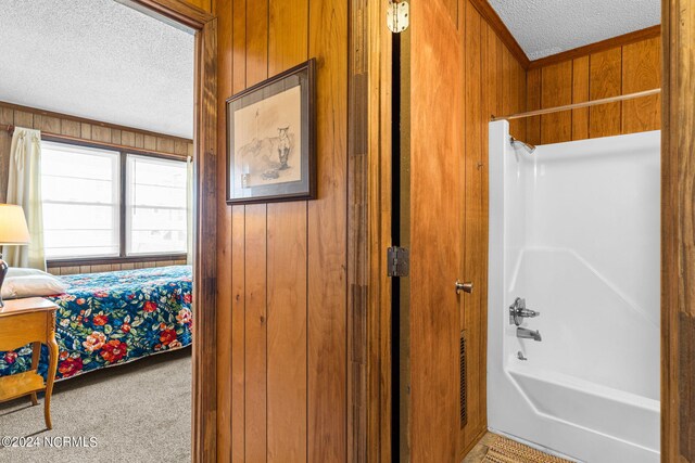 bathroom featuring a textured ceiling, shower / tub combination, and wood walls