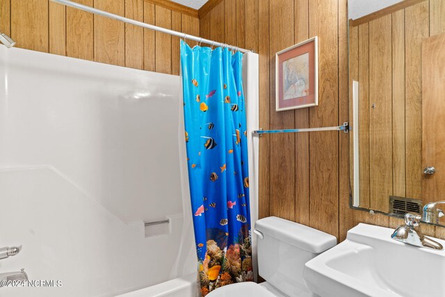 full bathroom featuring shower / bathtub combination with curtain, wooden walls, sink, and toilet