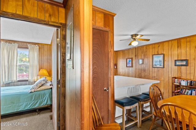 interior space with wooden walls, carpet, a textured ceiling, and vaulted ceiling