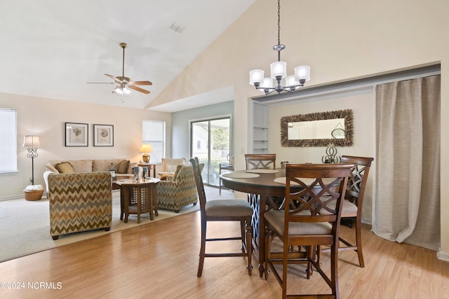 dining area featuring high vaulted ceiling, ceiling fan with notable chandelier, and light hardwood / wood-style flooring