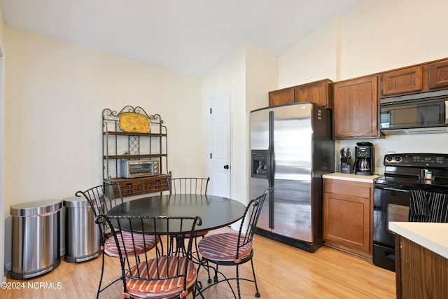 kitchen featuring black appliances, vaulted ceiling, and light hardwood / wood-style floors