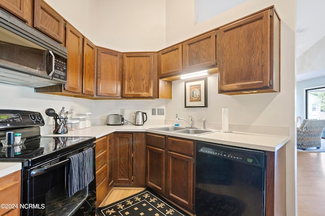 kitchen with black appliances, light hardwood / wood-style flooring, and sink