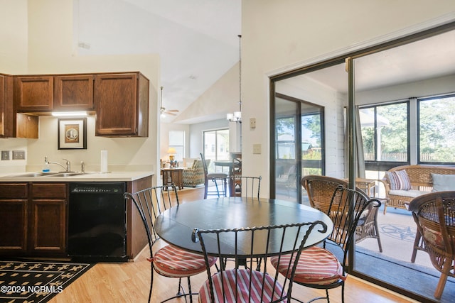 dining area featuring light wood-type flooring, high vaulted ceiling, sink, and a notable chandelier