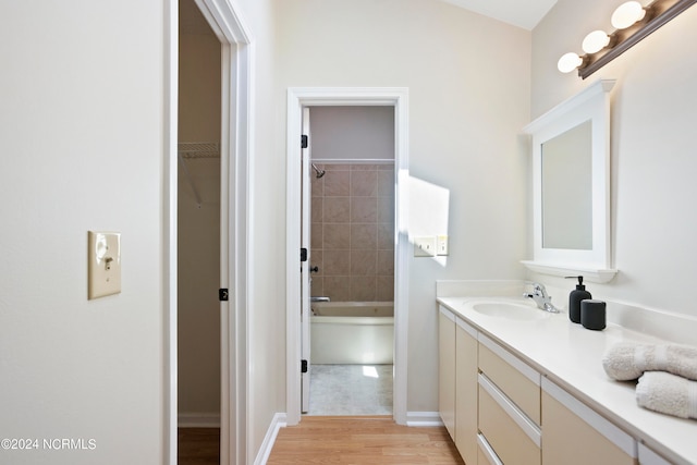 bathroom featuring hardwood / wood-style flooring, tiled shower / bath combo, and vanity