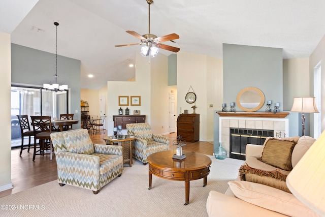 living room with high vaulted ceiling, ceiling fan with notable chandelier, wood-type flooring, and a fireplace