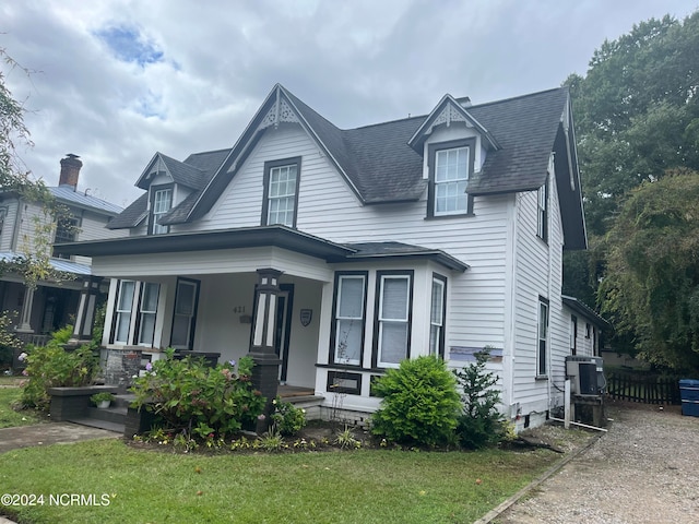 view of front of home featuring covered porch, a front yard, and central air condition unit