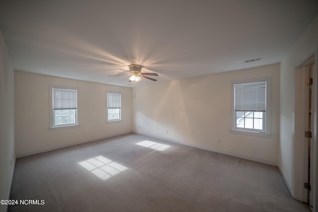 unfurnished room featuring light carpet, baseboards, visible vents, and a ceiling fan