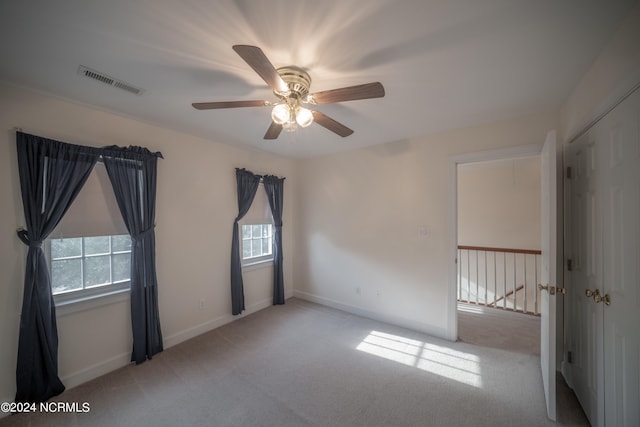 unfurnished room with a wealth of natural light, visible vents, and light colored carpet