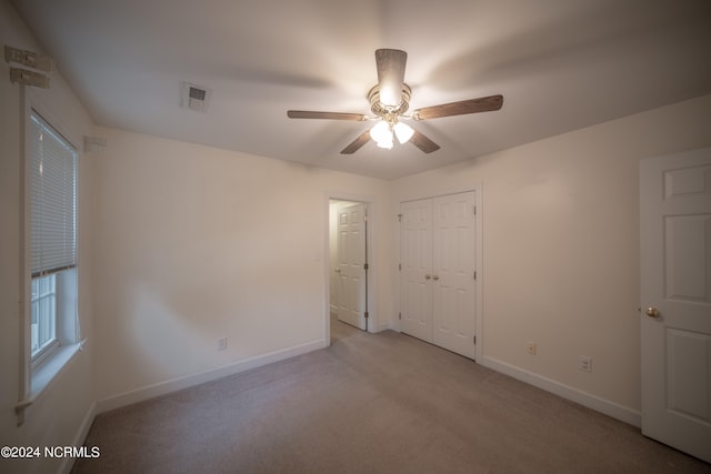 unfurnished bedroom with a closet, light colored carpet, visible vents, a ceiling fan, and baseboards