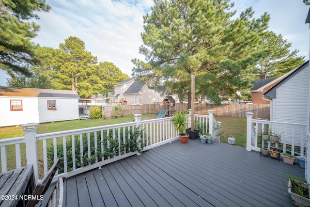 wooden deck featuring a fenced backyard, a residential view, a yard, an outdoor structure, and a playground