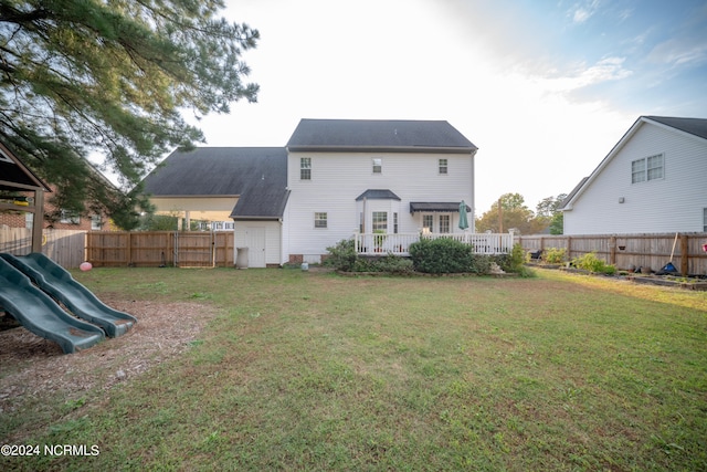 back of house featuring a playground, a lawn, and a fenced backyard