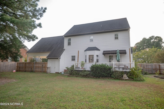 back of property featuring fence, a deck, and a lawn