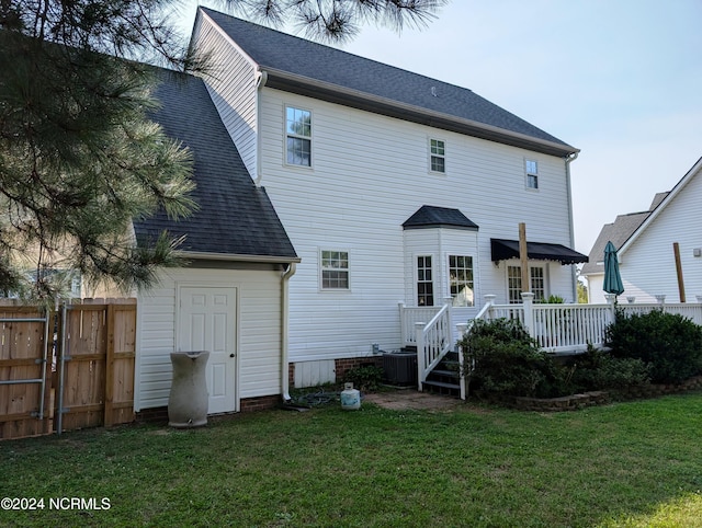 back of house featuring a shingled roof, fence, a lawn, and central AC