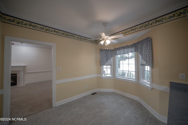 spare room with ceiling fan, ornamental molding, a fireplace, and baseboards