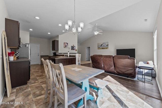 dining space with vaulted ceiling, sink, and ceiling fan with notable chandelier